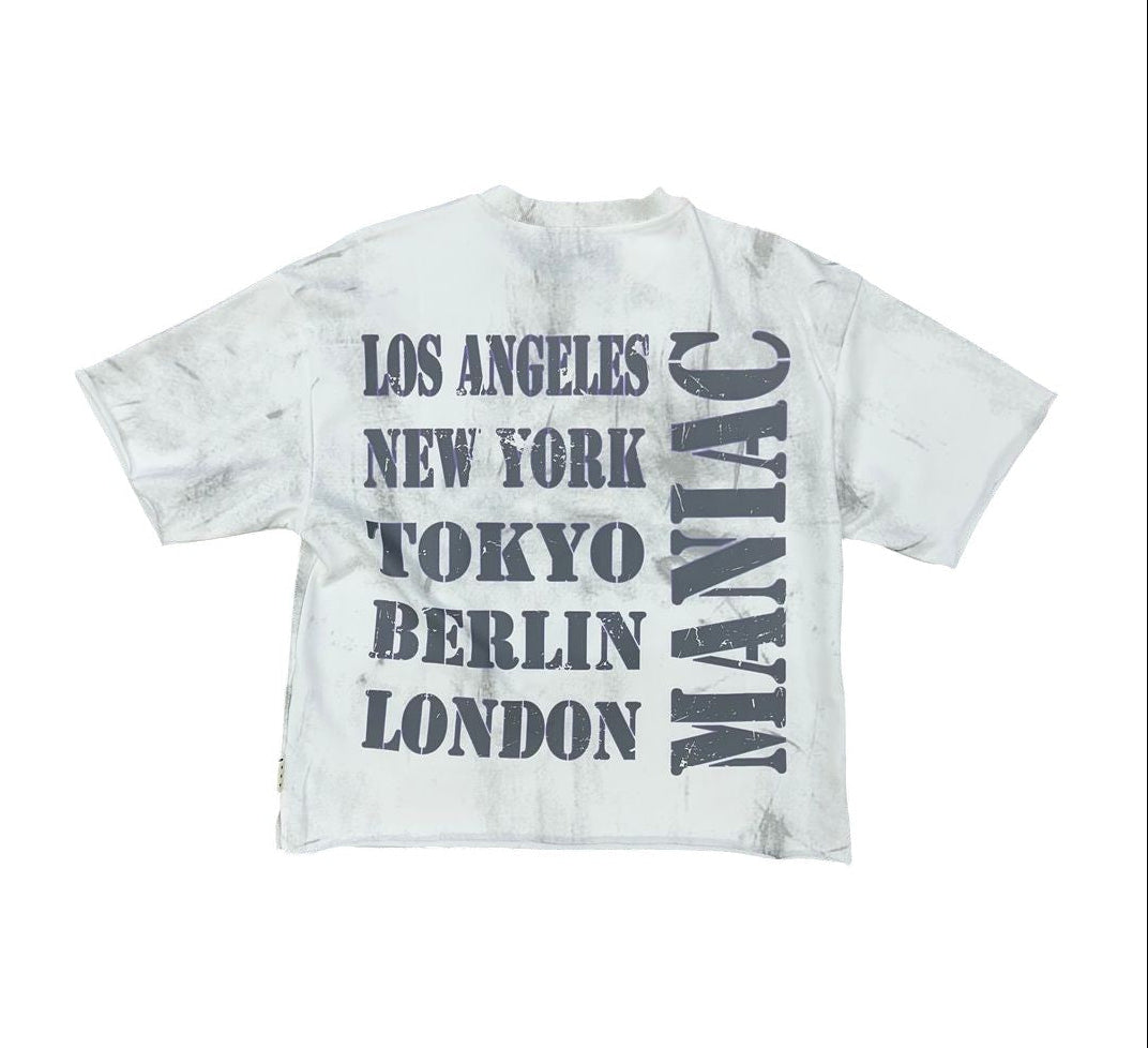 On Time Fashions white cropped tee with distressed grey text listing cities: Los Angeles, New York, Tokyo, Berlin, London, and "Maniac".