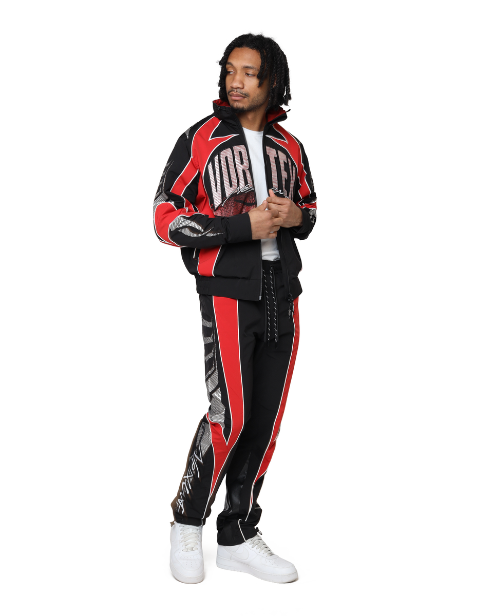 Person wearing a black and red tracksuit with visible branding on a white background