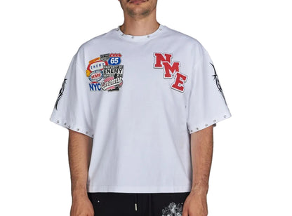 Person wearing a white t-shirt with various patches on a gray background