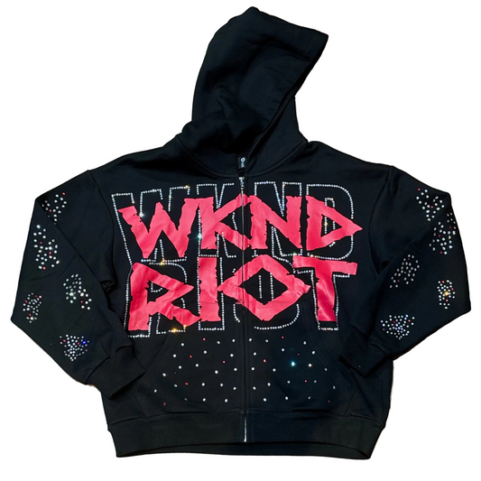 Black hoodie with pink 'WIND RIOT' text and rhinestone embellishments on a wooden floor.