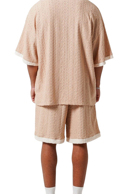 On Time Fashions beige crochet resort set with short-sleeved tee and shorts featuring textured openwork fabric and embroidered logos.