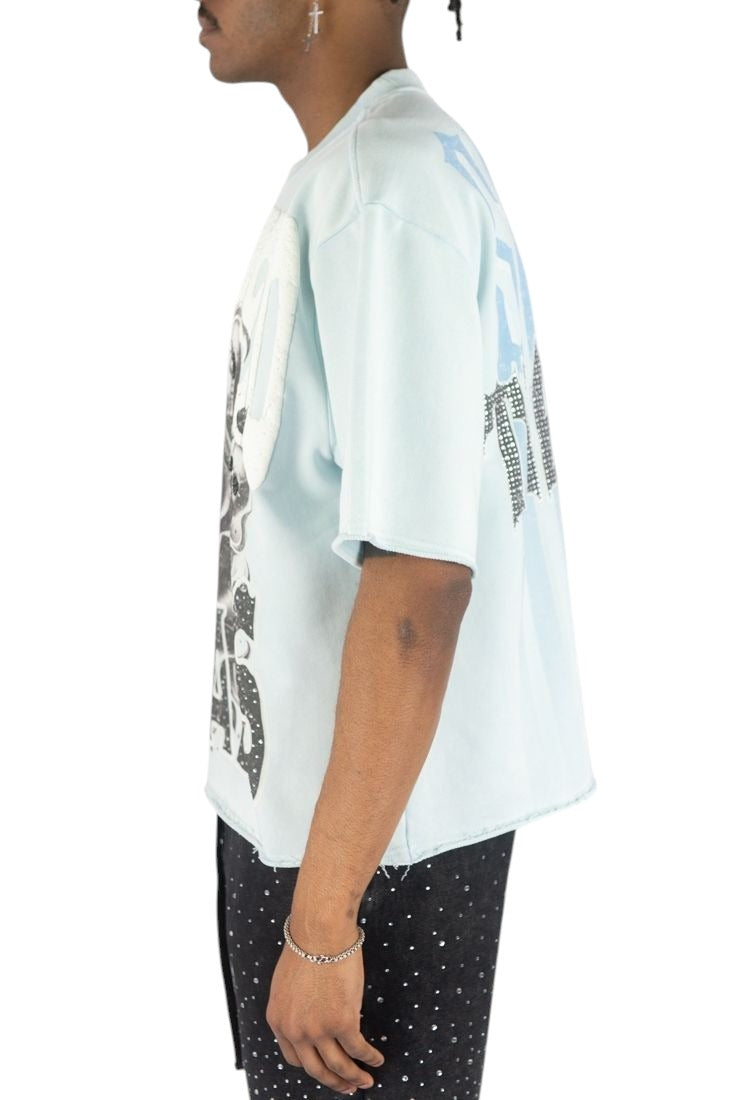 On Time Fashions light blue Rebel Minds crop tee with skull and rose graphic, rhinestones, and raw-edge hem.