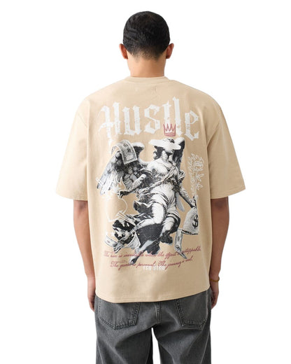 On Time Fashions tan heavy terry t-shirt with a graphic print of an angel holding money bags and dollar bills, with the word "Hustle" above.