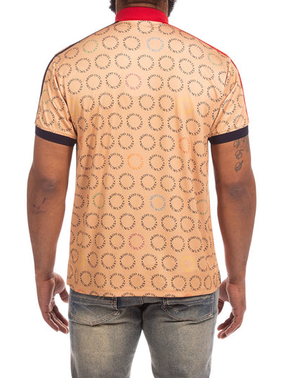 On Time Fashions Akoo Captain Polo shirt in tan with all-over circular logo print, red collar, and dark trim.