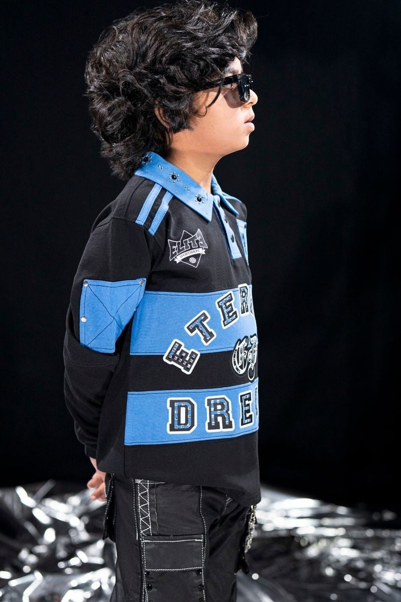 On Time Fashions black and blue long-sleeve polo shirt with "Eternal Dreams" graphic, embellished collar, and oversized fit for kids.