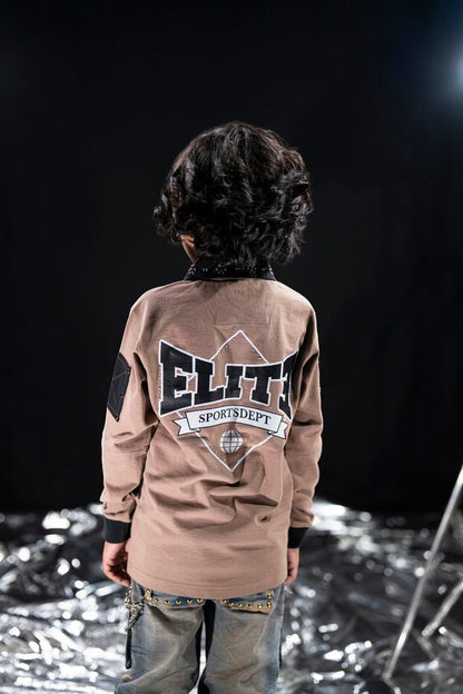 On Time Fashions kid's brown long-sleeve polo with oversized fit, featuring 'Elite Sportsdept' graphic with globe detail and studded collar.