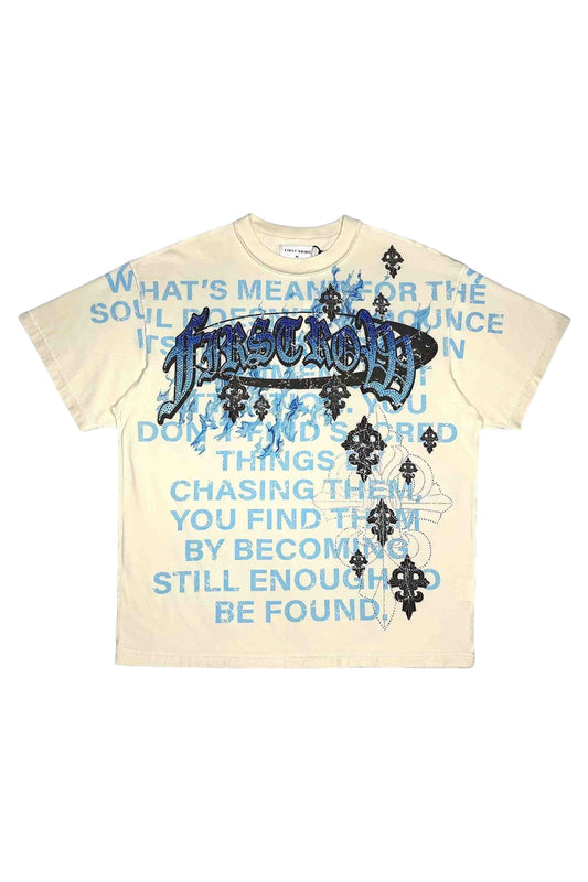On Time Fashions cream 100% cotton relaxed fit tee with blue text graphic and rhinestone detailing.
