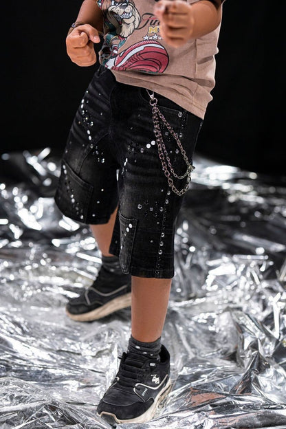 On Time Fashions black distressed denim shorts for kids with white paint splatters and silver stud details, featuring a detachable chain.