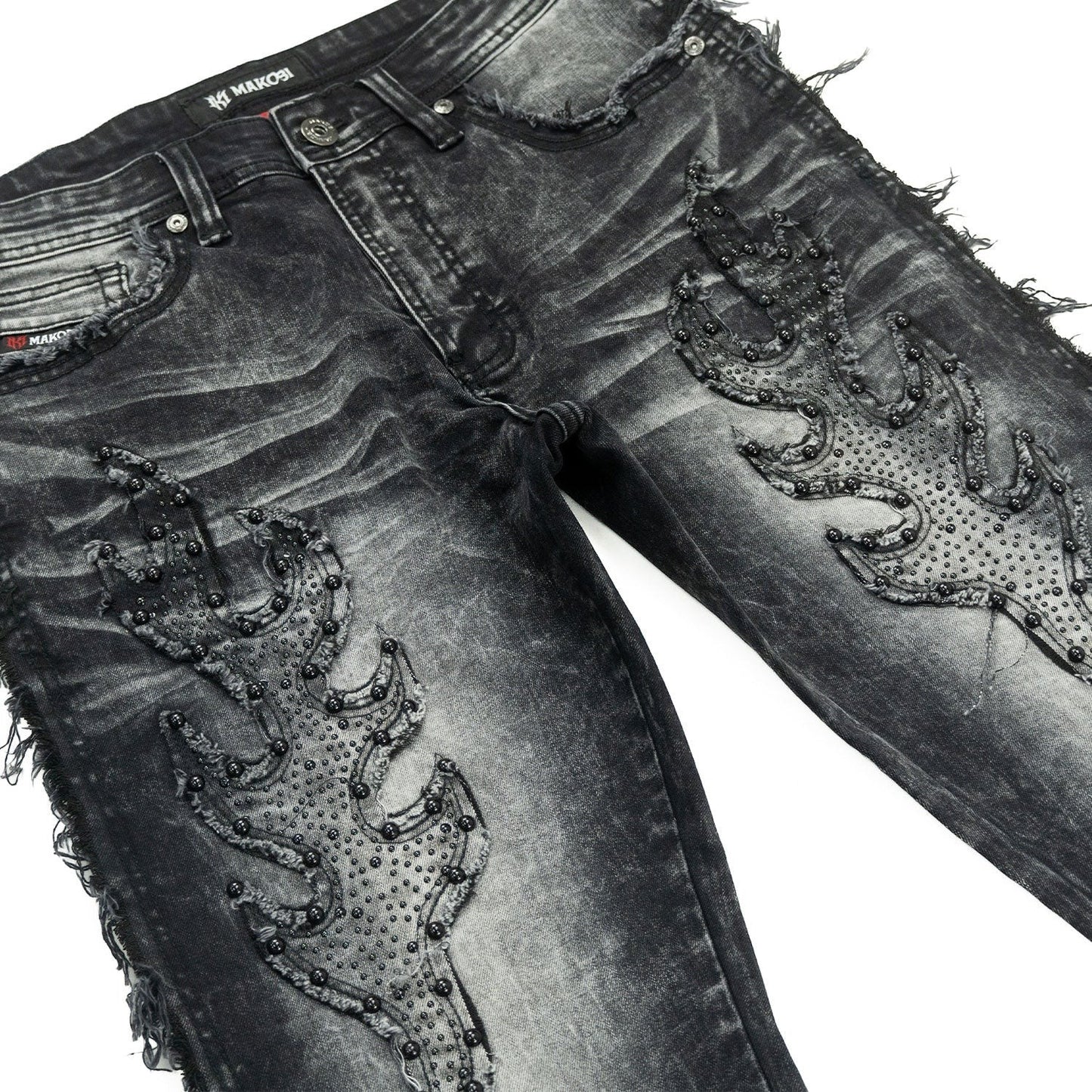 On Time Fashions Makobi Tesoro stacked jeans in black wash denim with flame-shaped bead embellishments and distressed frayed hems.