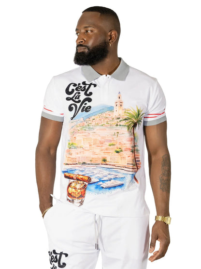 On Time Fashions white polo shirt with graphic print of a coastal city, palm trees, yachts, and a cigar with whiskey. Features "C'est La Vie" text.