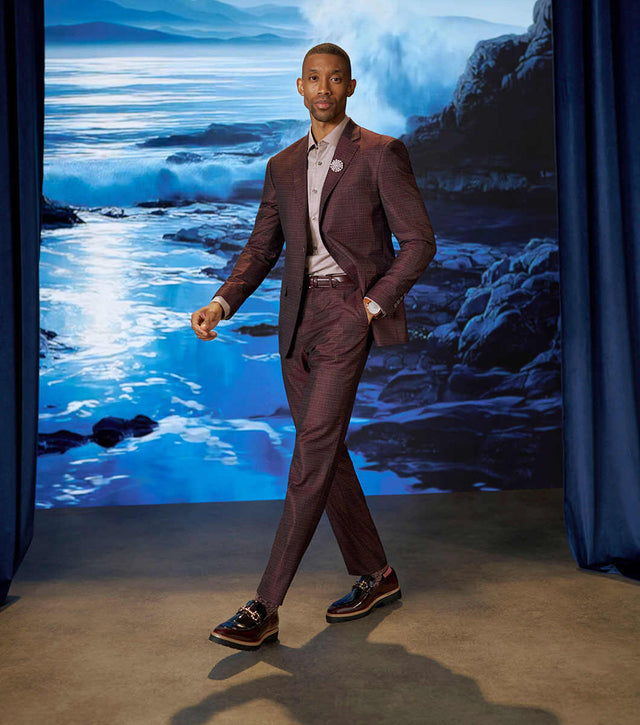 Model wearing Stacy Adams Carabello Burgundy Multi loafers with a burgundy outfit against a blue coastal stage backdrop.